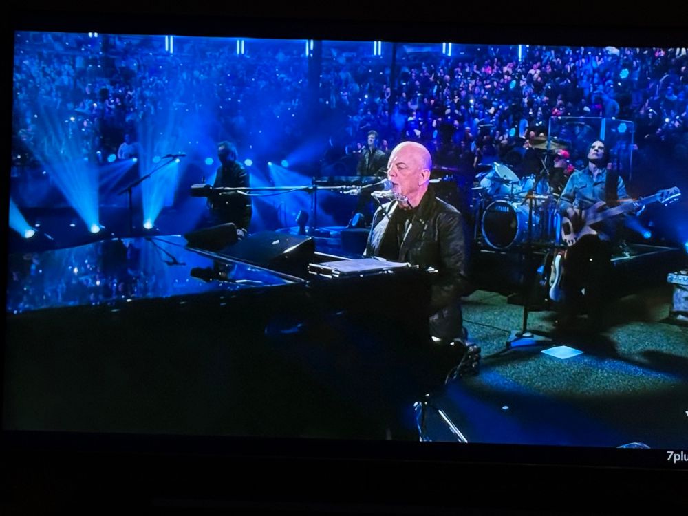 Billy Joel at piano with crowd in background 