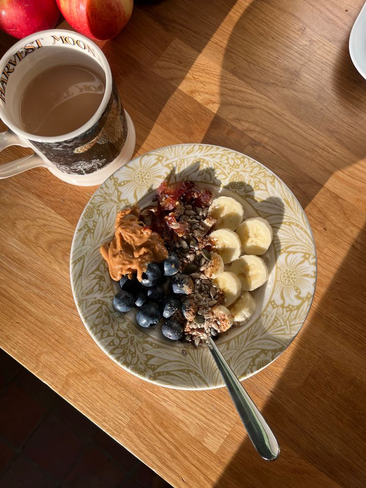 a bowl of the described meal, on a sunny wooden kitchen countertop with a cup of tea