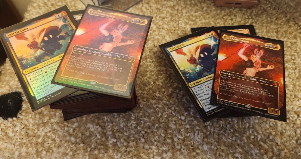 Two Magic the Gathering decks. On the left, a commander deck containing a holographic custom card of the poster's FFXIV character and a holographic Vivi, and on the right a standard deck containing  a non-holographic custom card of the poster's FFXIV character and a non-holographic Vivi