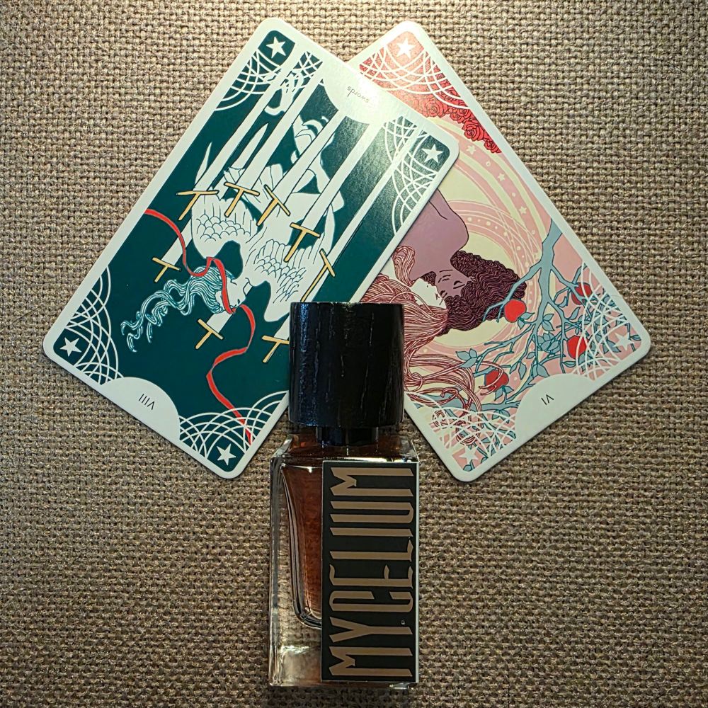 Rersed card VI - the Lovers is covered bya reversed VIII of Swords, and overlapping them is a bottle of Mycelium by Hayden Grossman for Treading Water Perfume