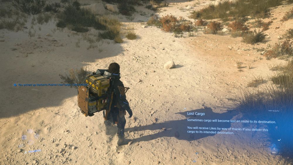 sam in Death Stranding 2 standing in a deserty rocky open space with a notification that he has just picked up cargo lost by Noberto Puente