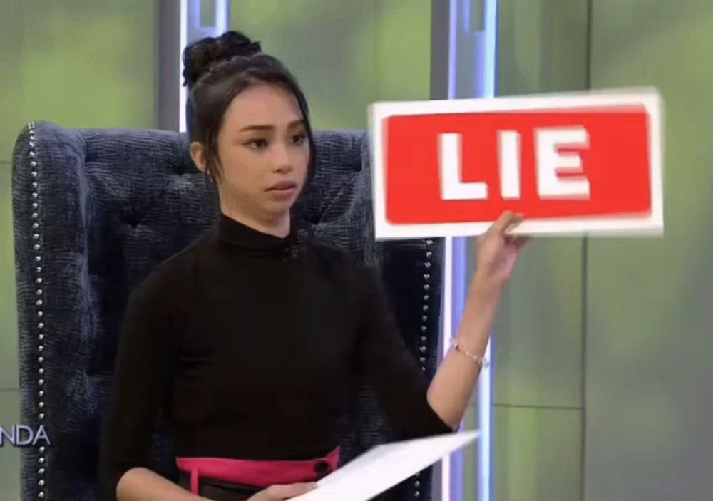 a woman holding a sign that says lie on it