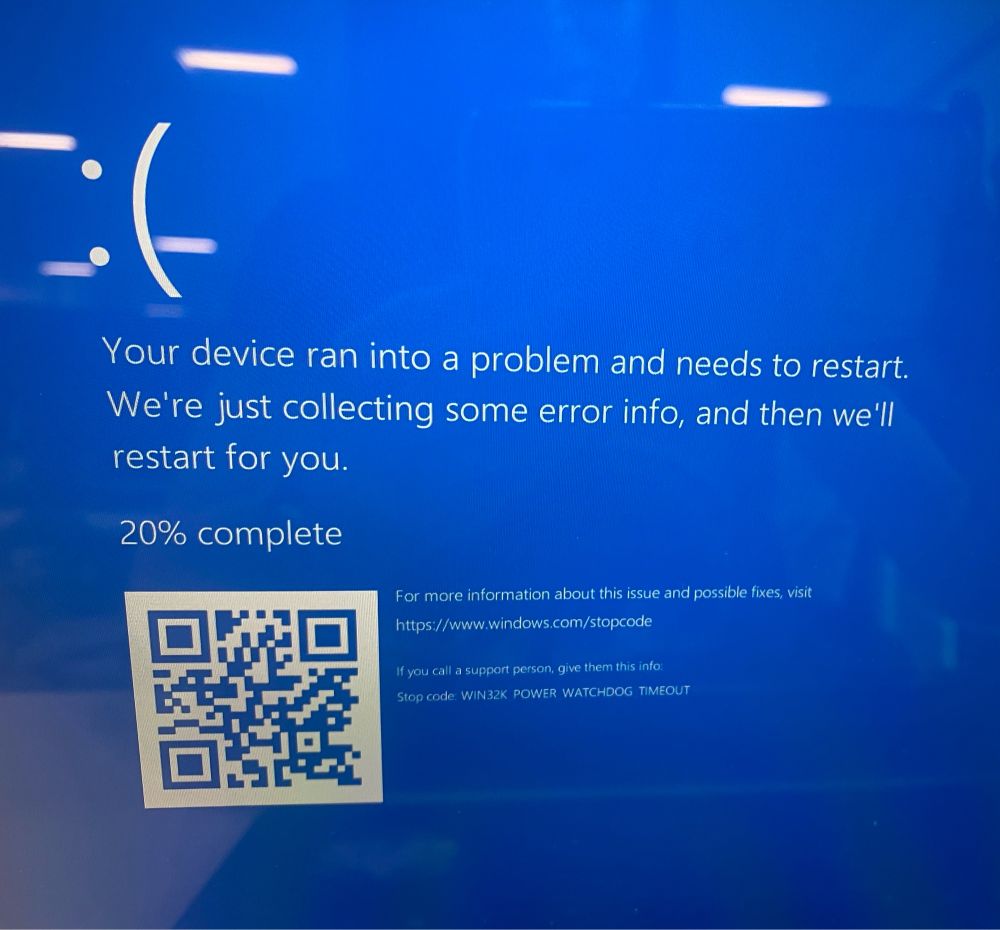 Photo of a Microsoft error screen. The screen has turned blue. There is a sad face emoticon, and then an error message saying the device has run into a problem and is restarting.