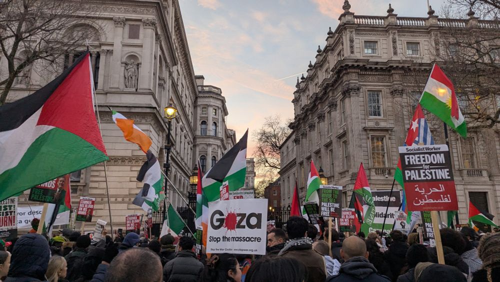 Crowds of people in London, outside Fishing Street, for a rally for Palestine. Many are carrying Palestinian flags.