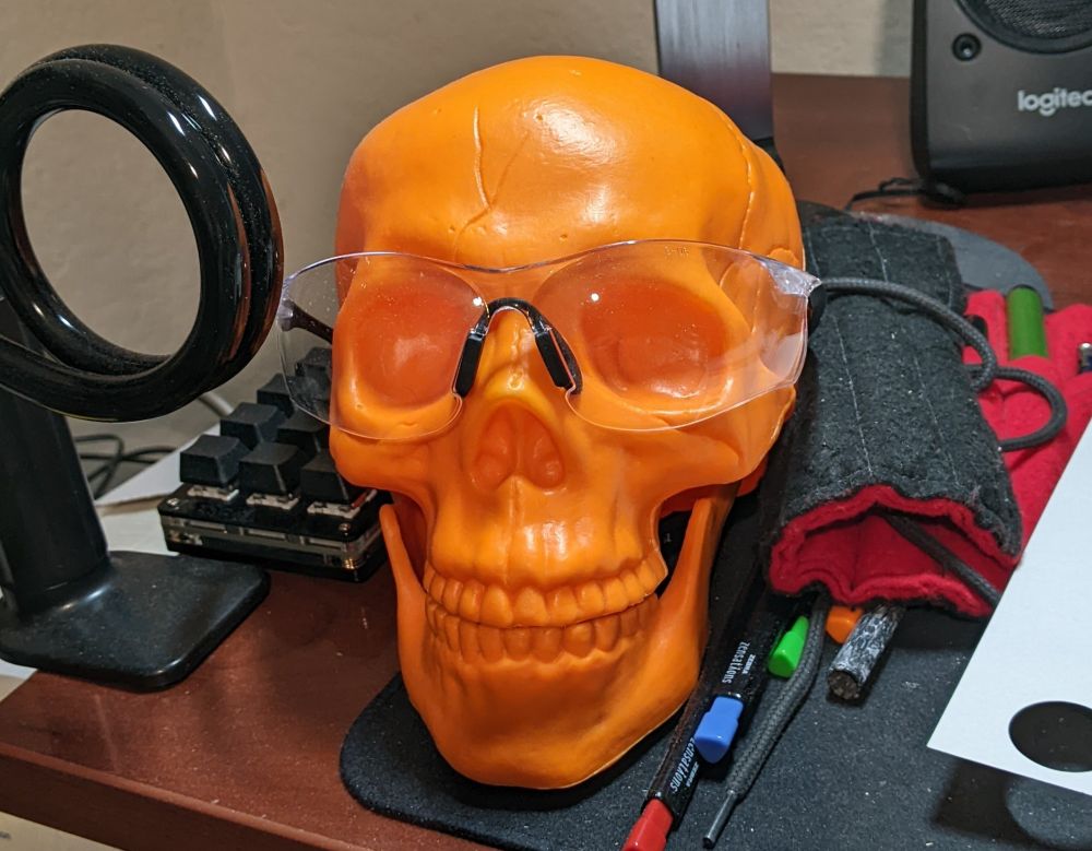 Orange plastic skull wearing safety glasses.
