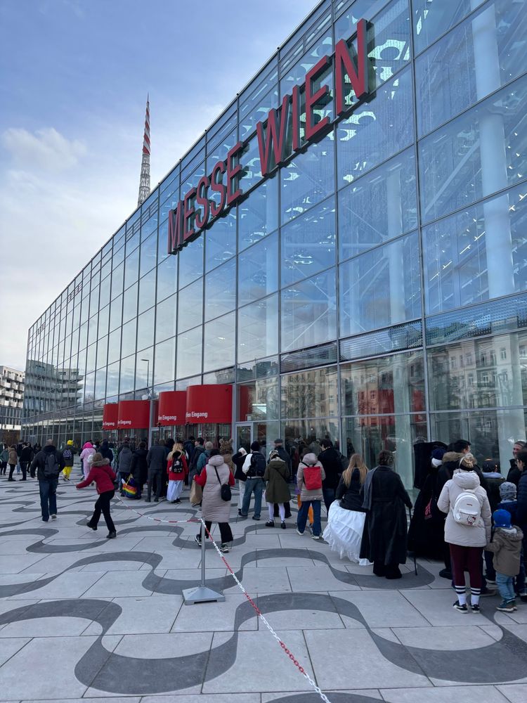 Foto vor der Messe Wien. Man sieht eine Glasfront das Gebäude und davor eine lange Schlange mit anstehenden Menschen.