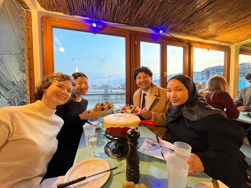 Students smiling and posing at a table with Swiss cheese fondue
