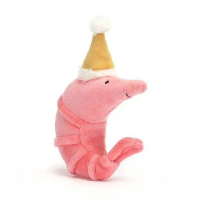 product photo of Jellycat brand plush toy called "Celebration Crustacean Shrimp," a smiling pink prawn sitting up in a C-shape with a little golden santa hat on