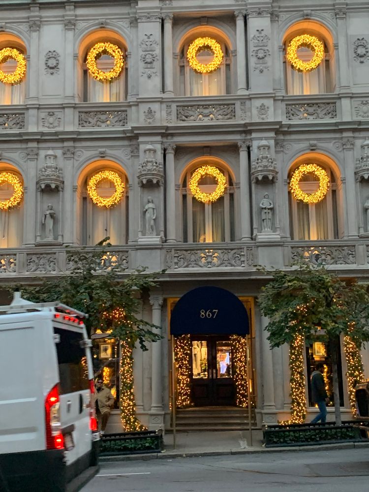 Building in brightly lit wreaths in every window. Lit trees are flanking the entrance. 