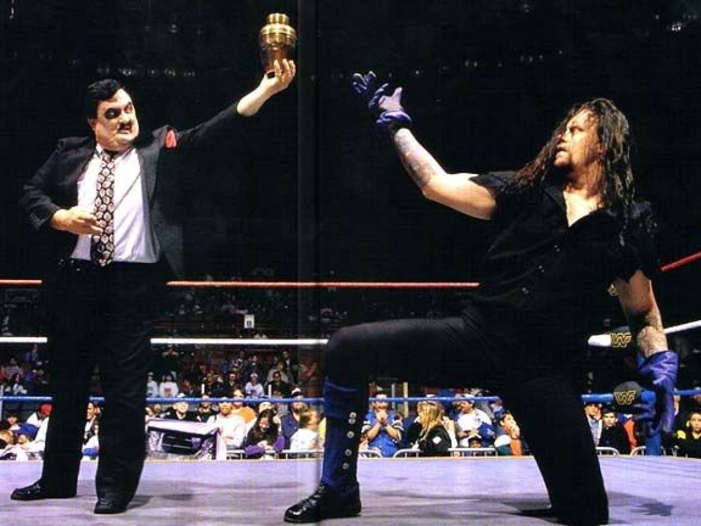 The Undertaker and Paul Bearer in 1994. The Undertaker is kneeling in a literal sense.