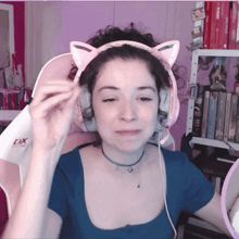 a woman wearing pink headphones with cat ears is sitting in a dx chair