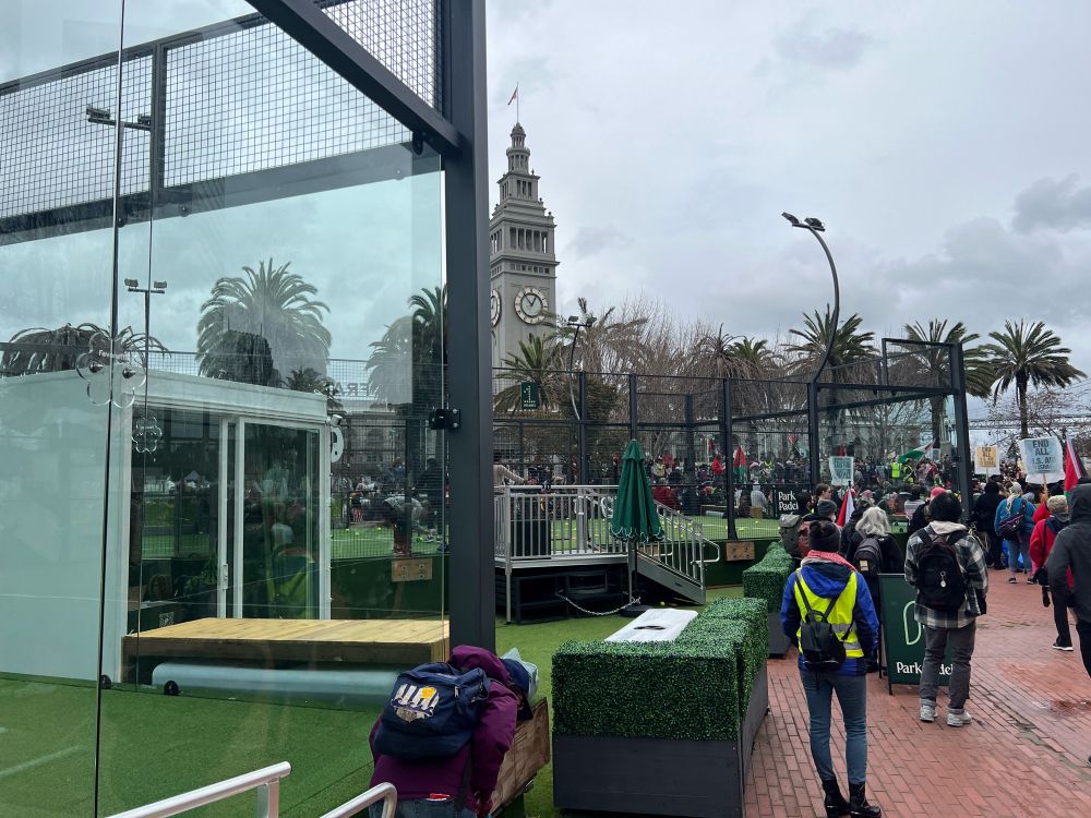 People inexplicably learning pickleball in some popup courts in Harry Bridger plaza while a large pro ceasefire march starts