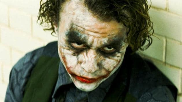 A picture of Heath Ledger's Joker, sitting in the interrogation room against the wall.
