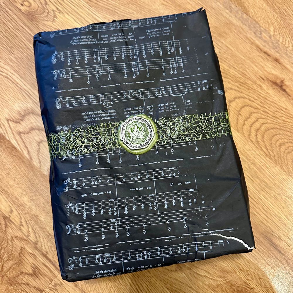 The package with the two Doomsong books, wrapped in black paper with some music sheet on it and sealed with the game's metal Doom Coin set in a green wax seal.