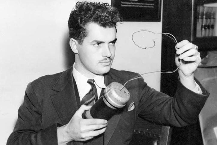 Photo of a well-dressed Jack Parsons, holding the replica car bomb used in the murder trial of police officer Captain Earl Kynette.