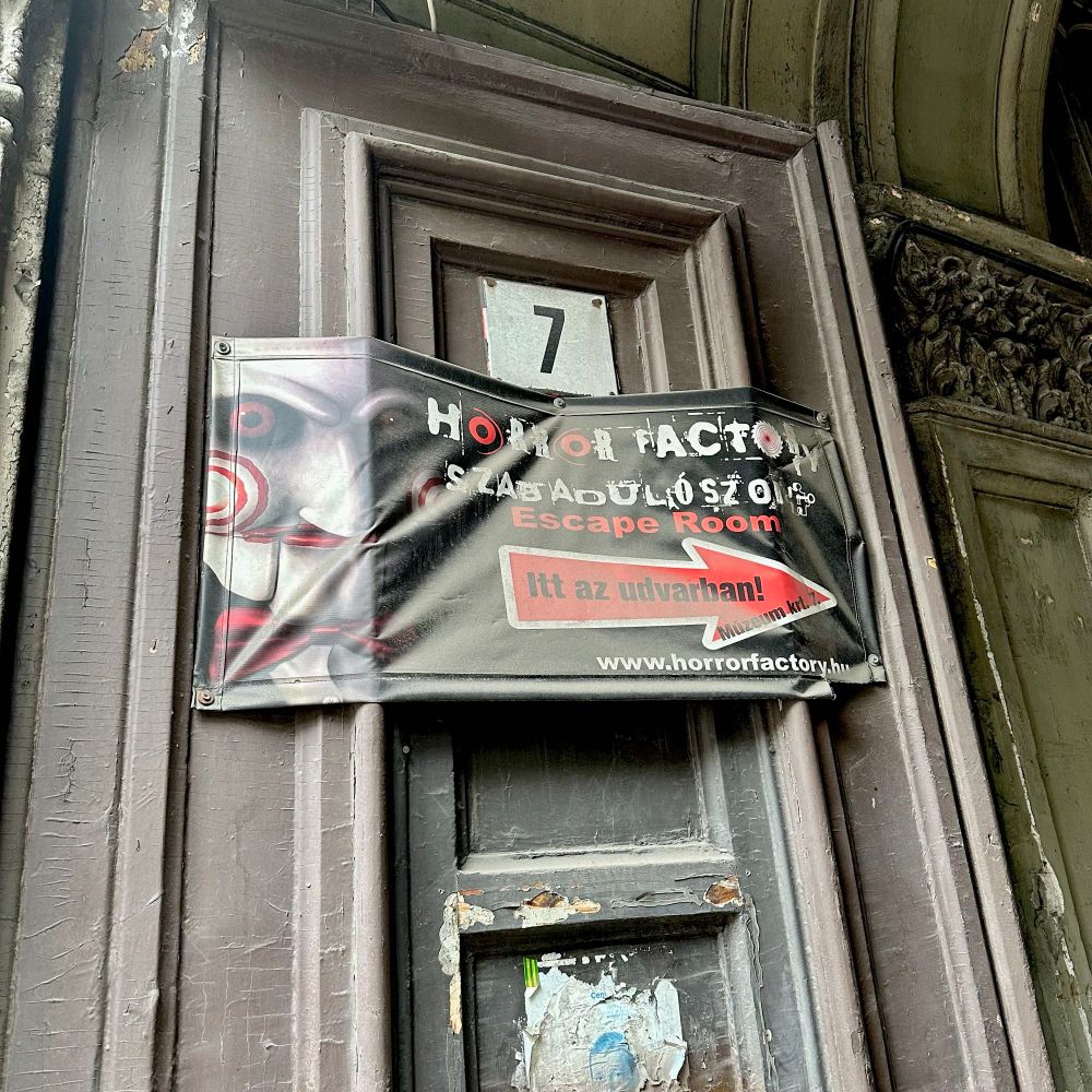 Advertisement for a Saw themed Escape Room hanging on a building wall in Budapest. 