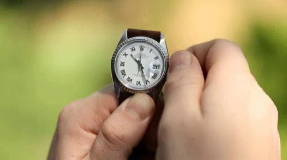 a person is adjusting a watch with roman numerals on it