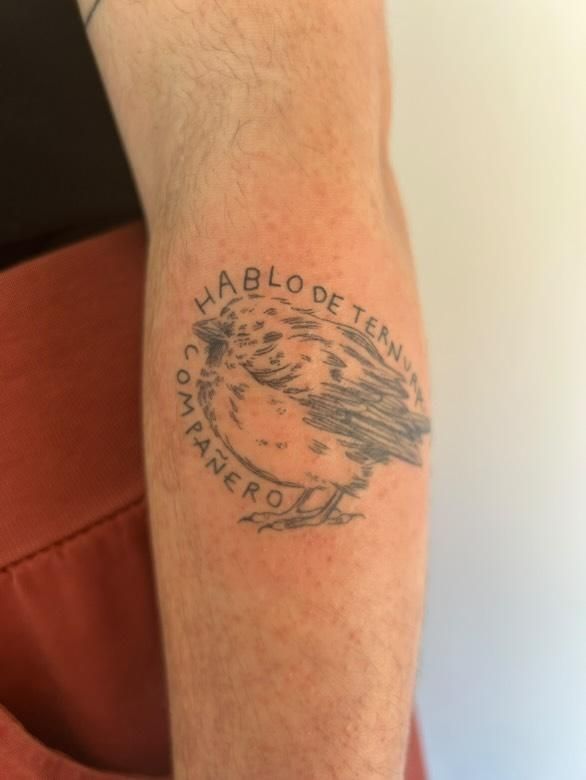 Es un tatuaje hecho en el antebrazo. Es un gorrión chiquitito hecho una bolita (monísimo) y está rodeado de una frase de Pedro Lemebel: «Hablo de ternura, compañero»