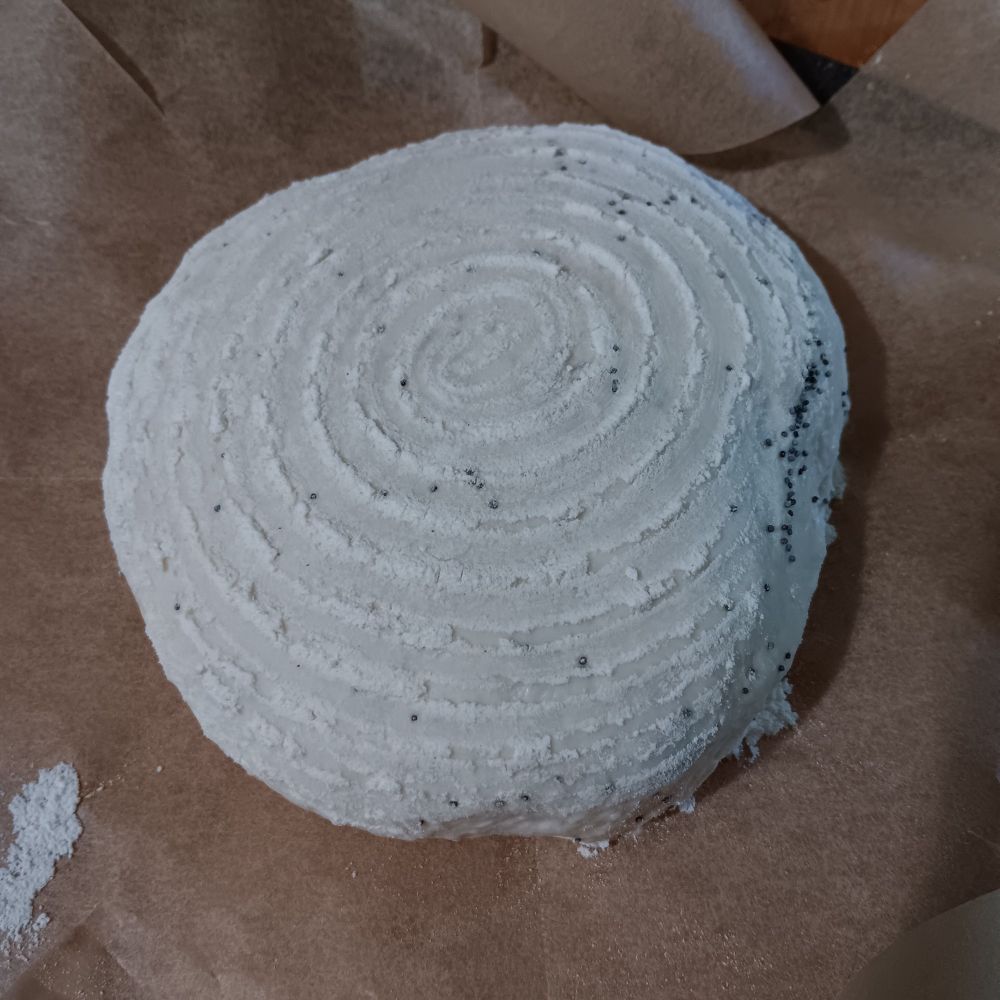 A picture of the loaf before baking- it is circular, and you can see the spiral outline of the proofing basket formed of flour. 