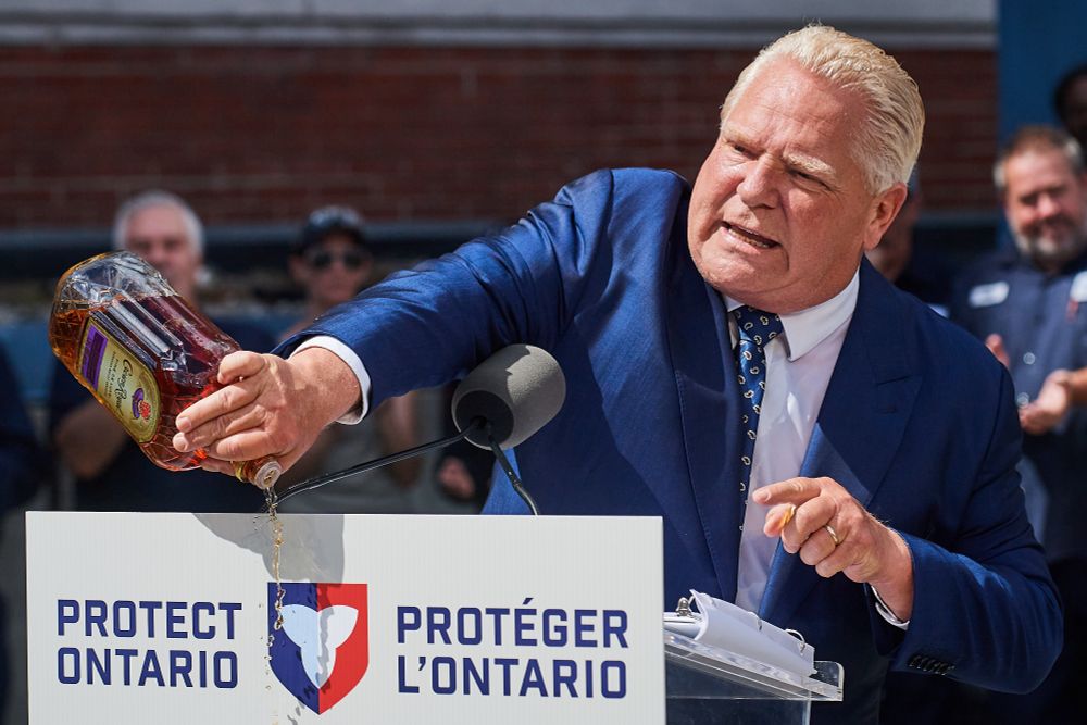 Doug ford pours a bottle of crown royal whiskey on the ground in front of a "protect ontario" podium 