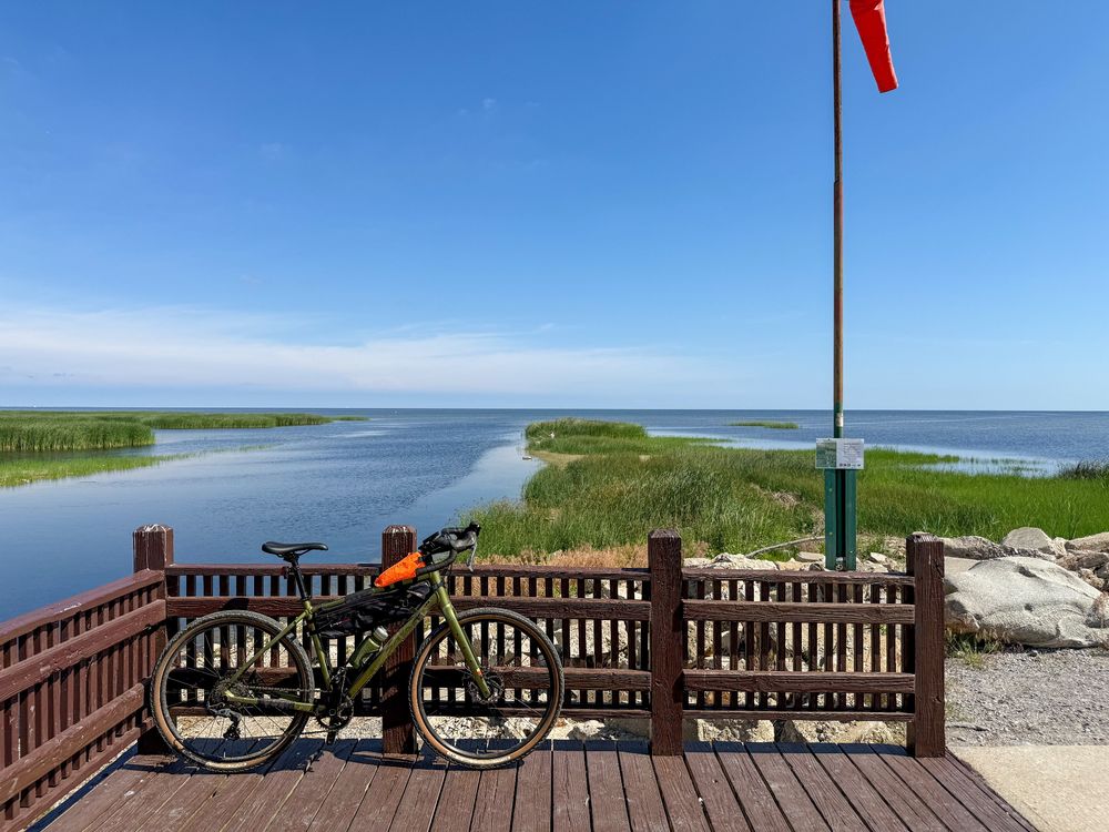A gravel bike leaning on the railing of a deck. Lake Huron (on the Michigan side) is in the background. 