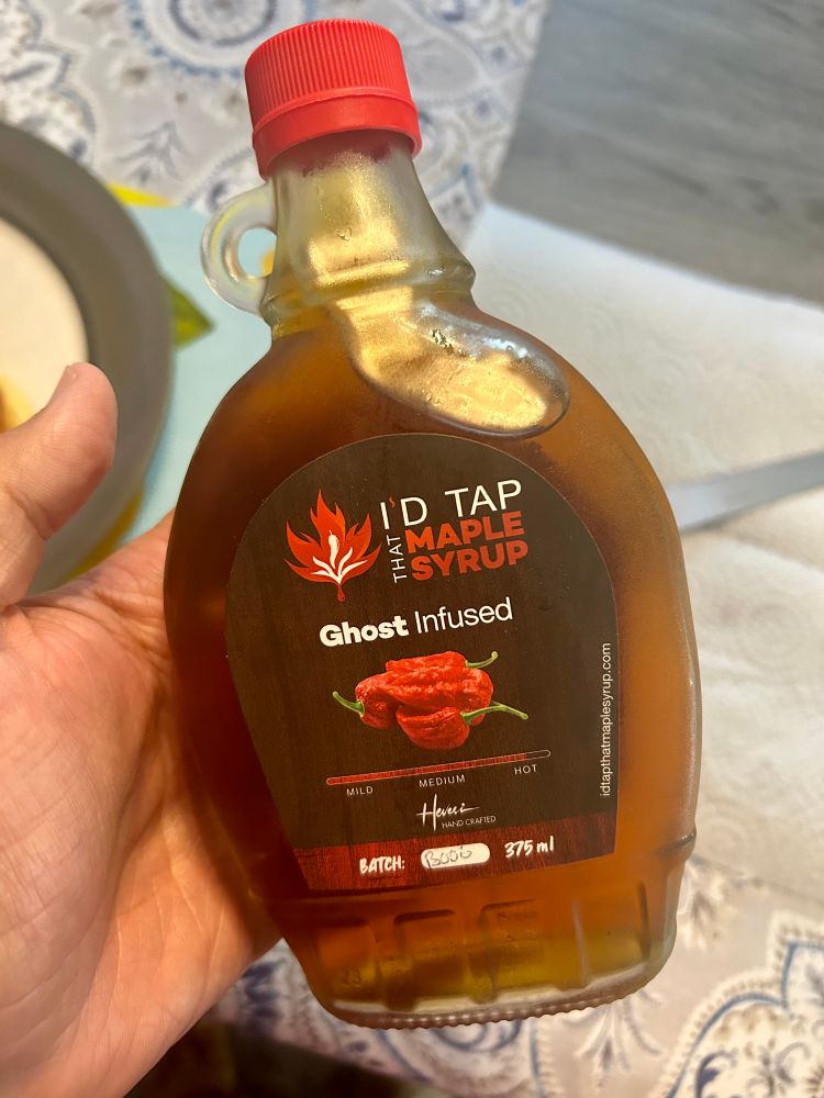 My hand holding a bottle of I’d Tap That’s ghost-pepper-infused maple syrup.