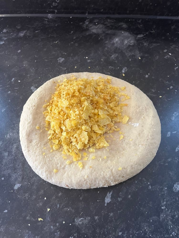 Smashed up crisps on flattened dough, yeast underneath them