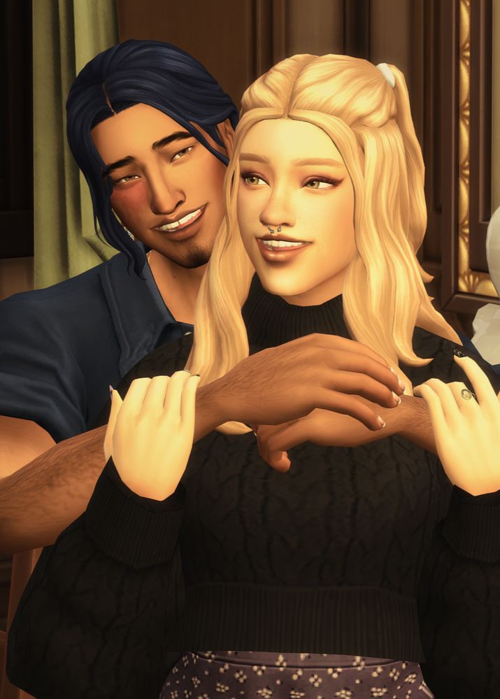 two of my genshin impact sims hugging and smiling. fischl in the front, a pale girl with long blonde hair and green eyes, wearing a black sweater, lauging and looking off camera. behind her, keaya embraces her friendlily. he is a tan sim with a birthmark under his right eye, long blue hair, and a blue shirt, smiling just beyond the camera