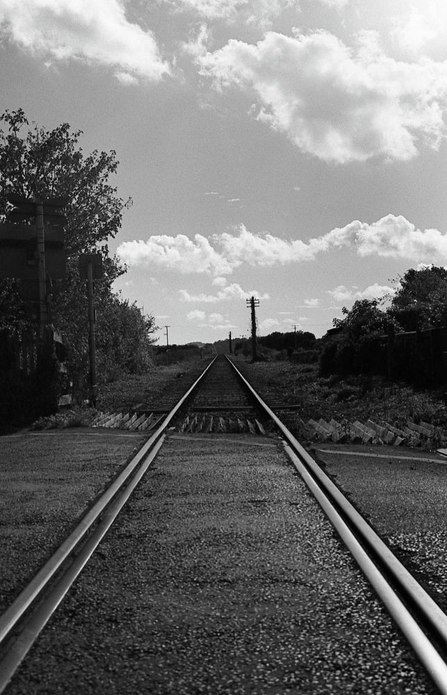 A black and white photo looking down the railway line of West Somerset Railway, heading towards Blue Anchor. The rails are straight and converge around the centre of the frame.