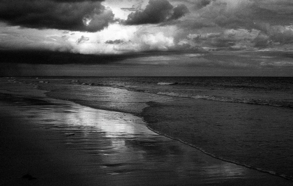 A black and white photo of an imposing sky above Batsardstown Beach in Ireland.
