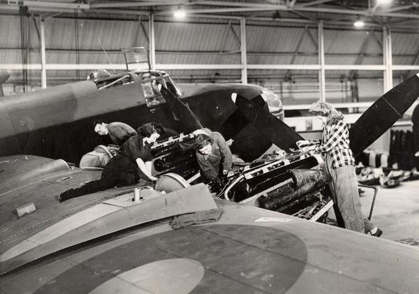 Three women workers shown installing the engines on the starboard wing of a Handley-Page Halifax bomber during the Second World War. The image was probably taken at Aldenham (LTPB factory no 2), where the assembly and installation of the central and front fuselage sections and engines were carried out; alternatively the location could be Leavesden factory, where the bombers were fully assembled and tested.