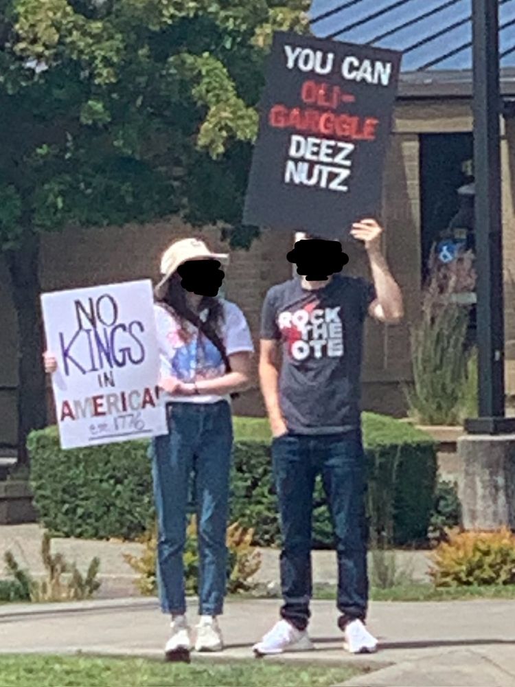 Signs from the No Kings march in downtown Kirkland, one of which says, “ogli-gargle deez nuts”.