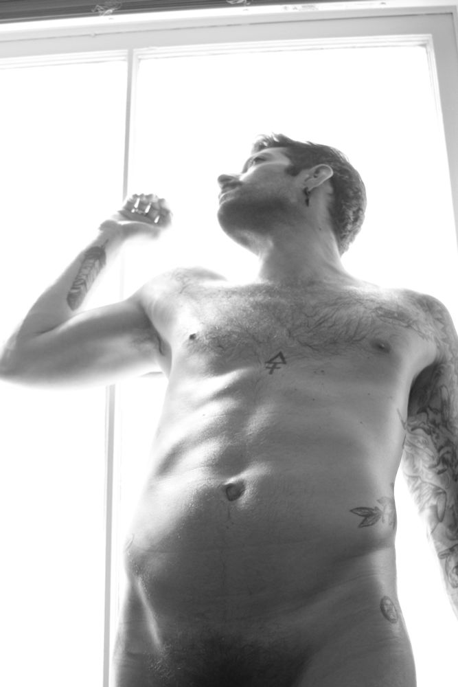 A nude RJ leaning on an open window basking in the sunlight as the photo is cropped right at his bush