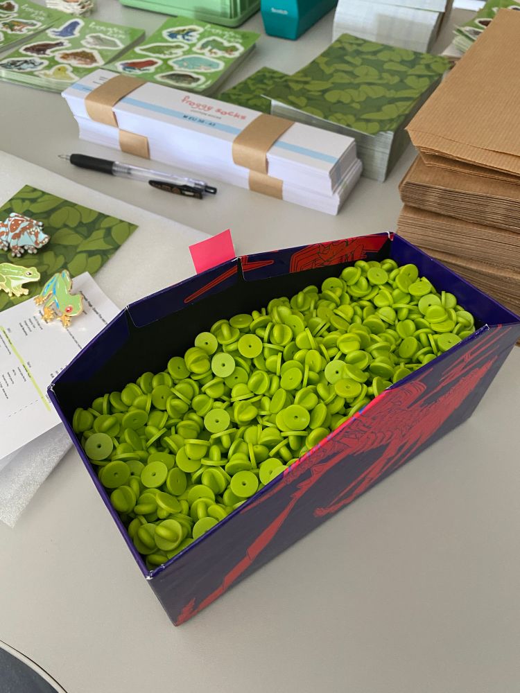 The same desk but now with a Pokemon ETB cardboard filled almost to the brim with bright green rubber clutches