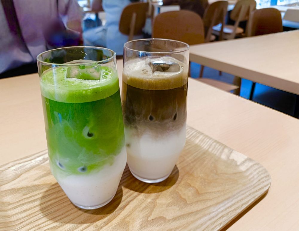 細長いグラスに入った抹茶ラテとほうじ茶ラテ。底の方にミルク、上の方に鮮やかなグリーンの抹茶でグラデーションになっている