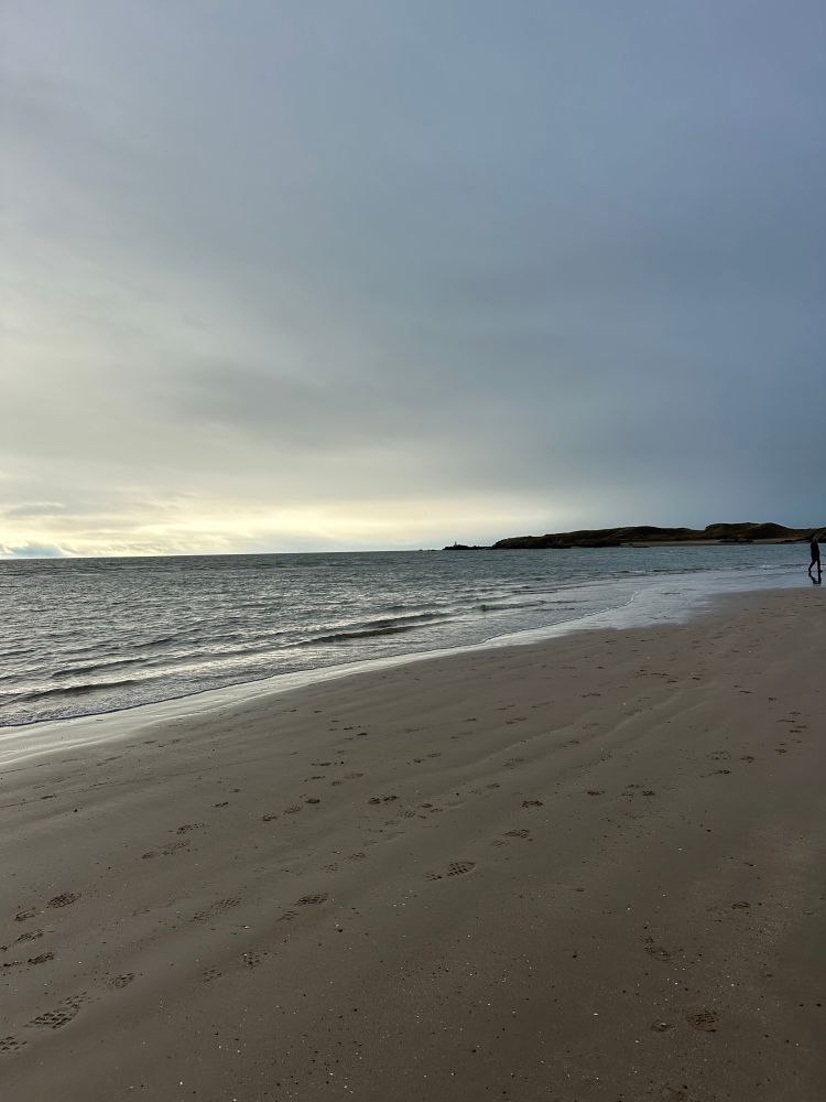 Newborough Beach on Anglesey. Sea on the left, sand on the right, tidal island headland in the background.