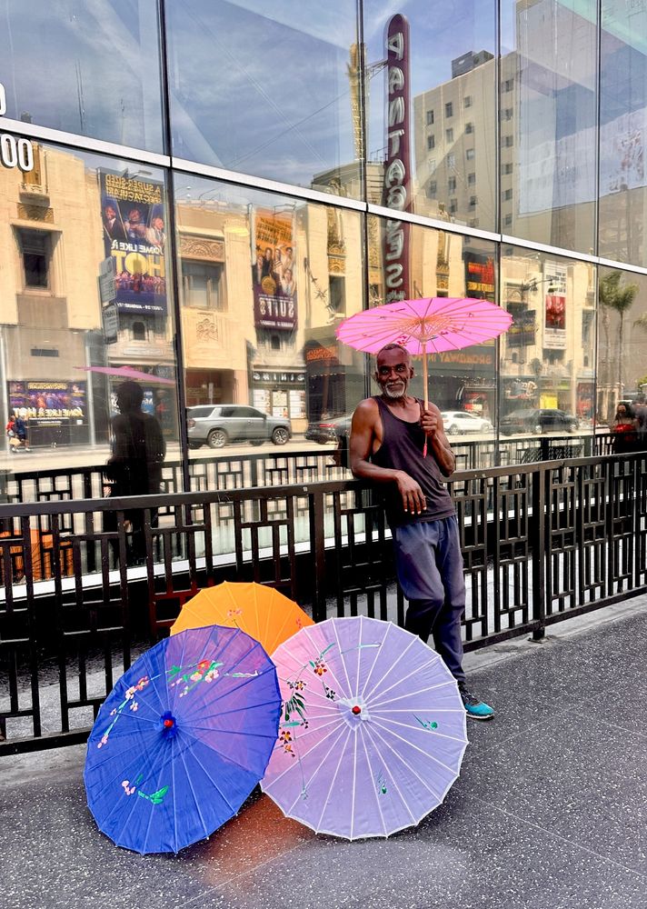 Smiling Black man selling colorful parasols in Hollywood. 