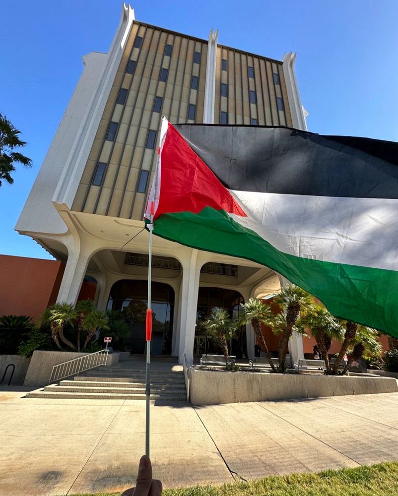 me holding up a palestinian flag in front of the UNLV humanities building where UNLV President Whitfield has his office