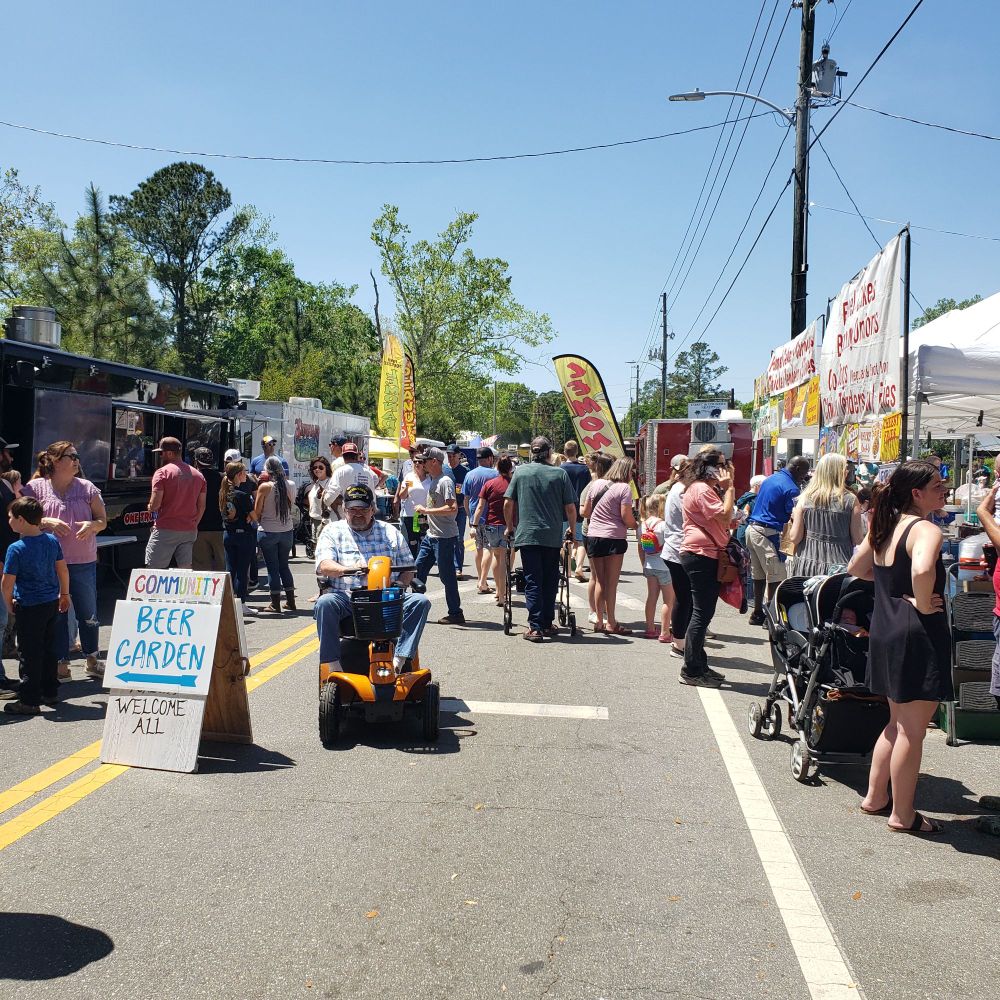 Huge crowd of people walking between vendors at the Sopchoppy Worm Festival