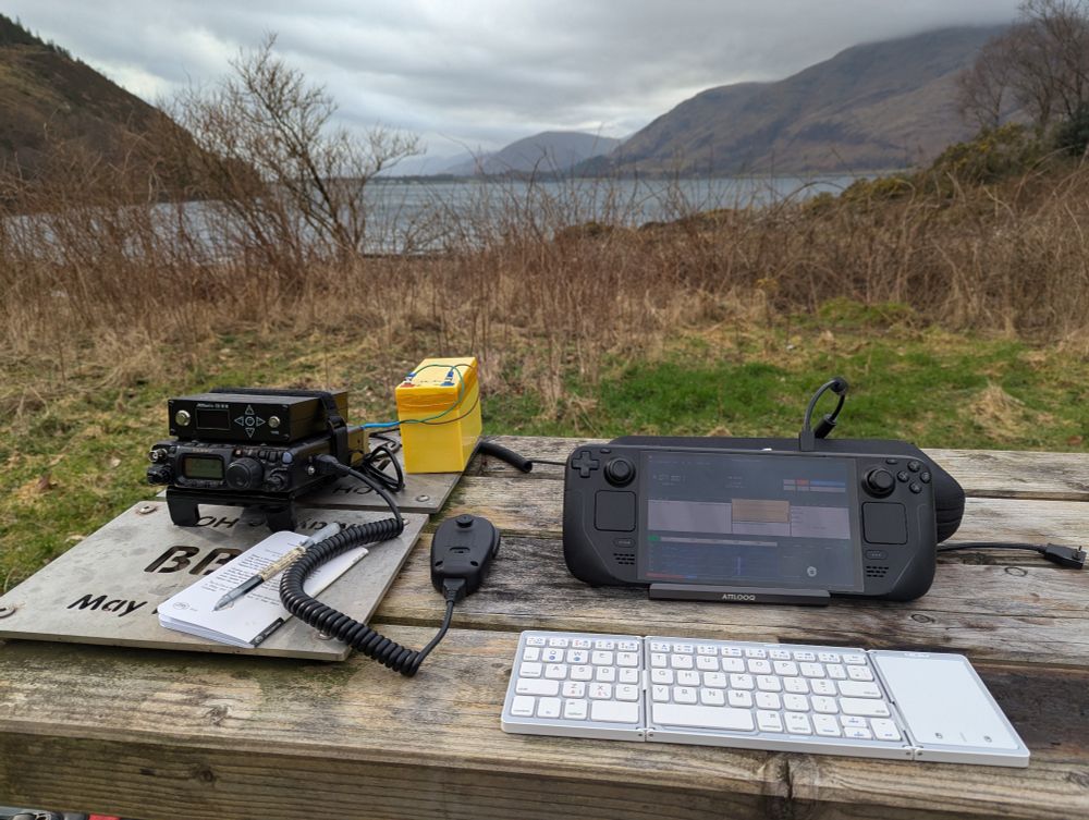Steam deck running js8 call on a picnic bench hooked up to FT 818 radio with a view across the loch.