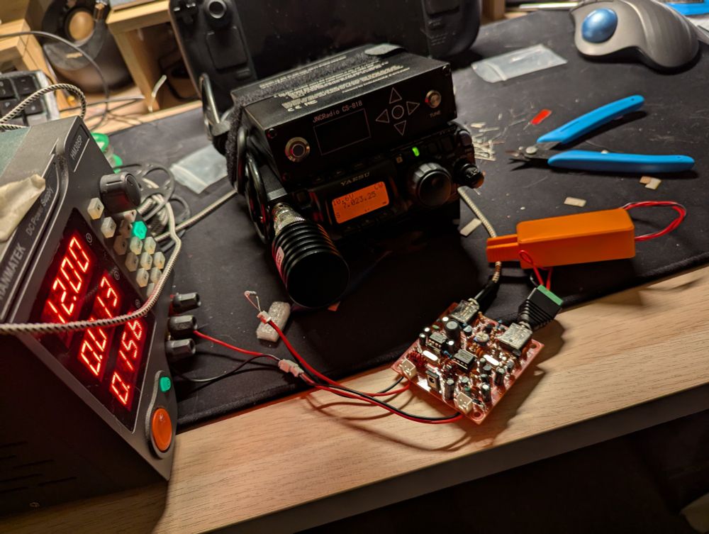 DIY morse code transceiver with 3D printed key hooked up to a bench power supply. Yaesu radio with dummy load in the background on a very messy desk.