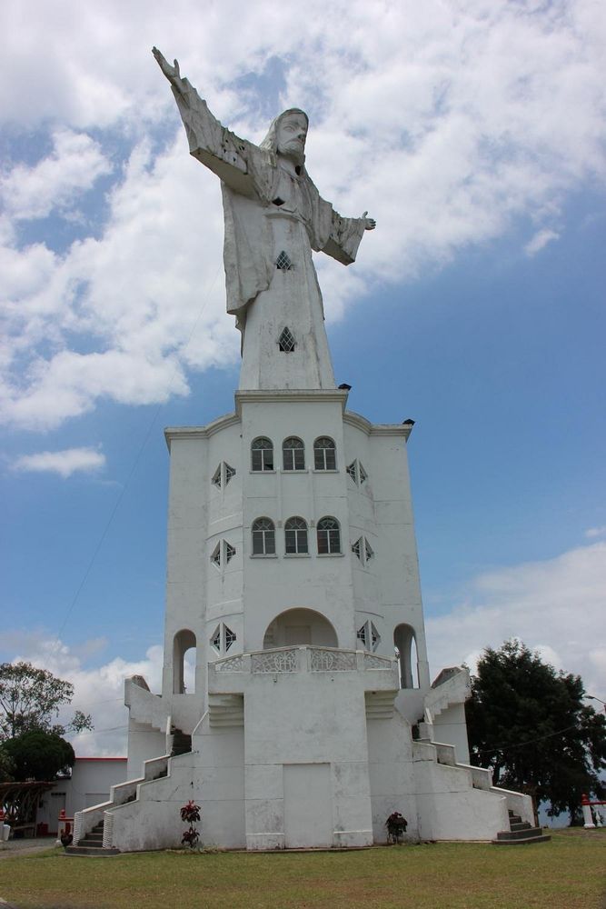 El Cristo Rey de Belalcázar, dreistöckiges weißes Gebäude mit einer riesigen Jesusstatue auf dem Dach. Jesus hat zahlreiche Treppenhausfenster. 