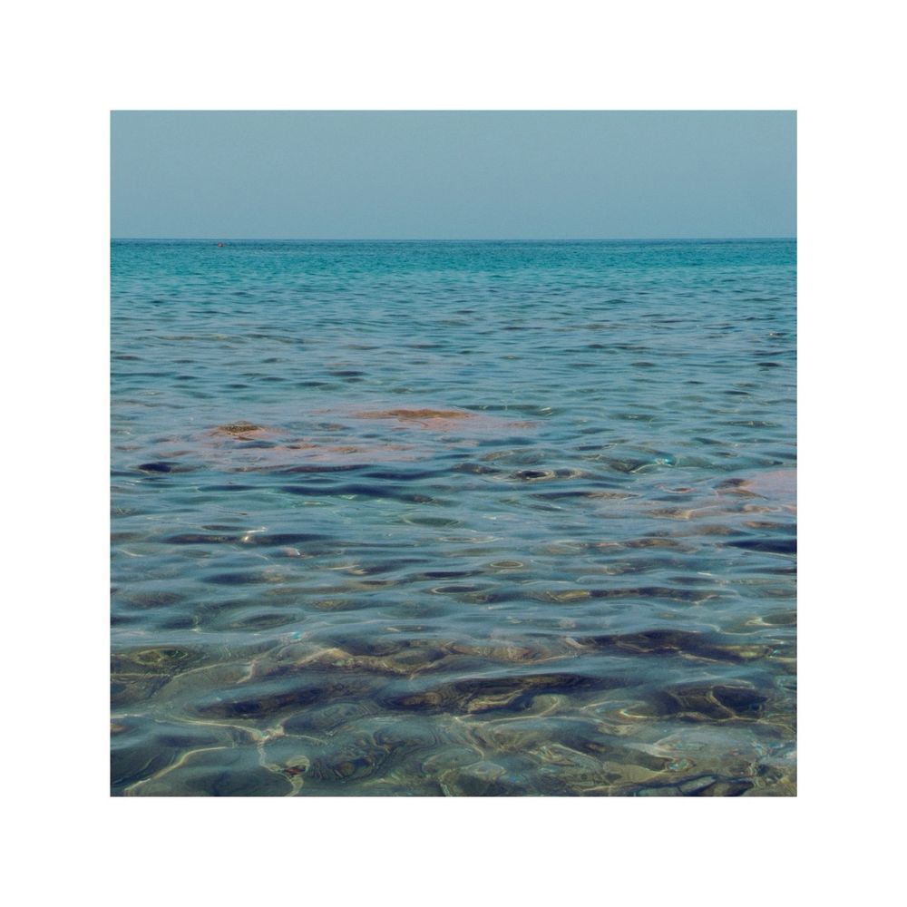 a straight look on a completely flat ocean. just some gentle ripples make the water alive. above a horizontal stripe of the turquoise sky. nothing else