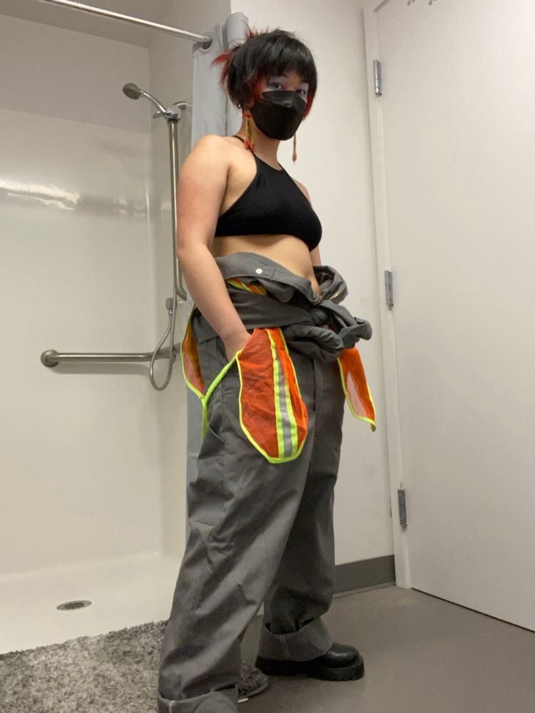 goth bitch stanced up in a worker jumpsuit costume half on like ellen ripley