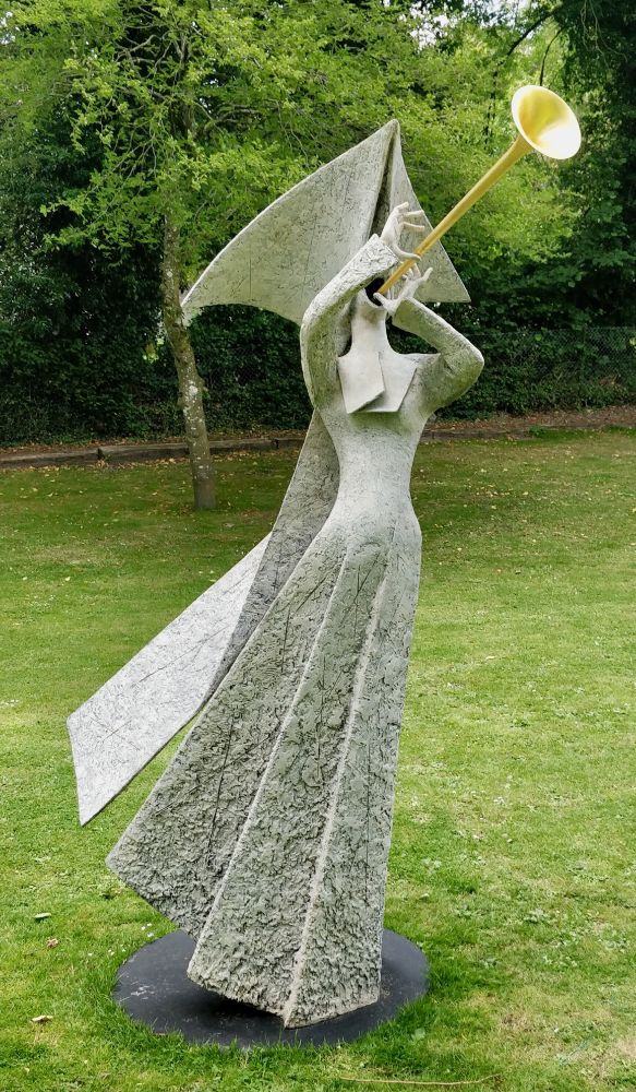 A sculpture by Philip Jackson of a female figure in a long dress, wearing a tricorn hat and blowing a brass trumpet.