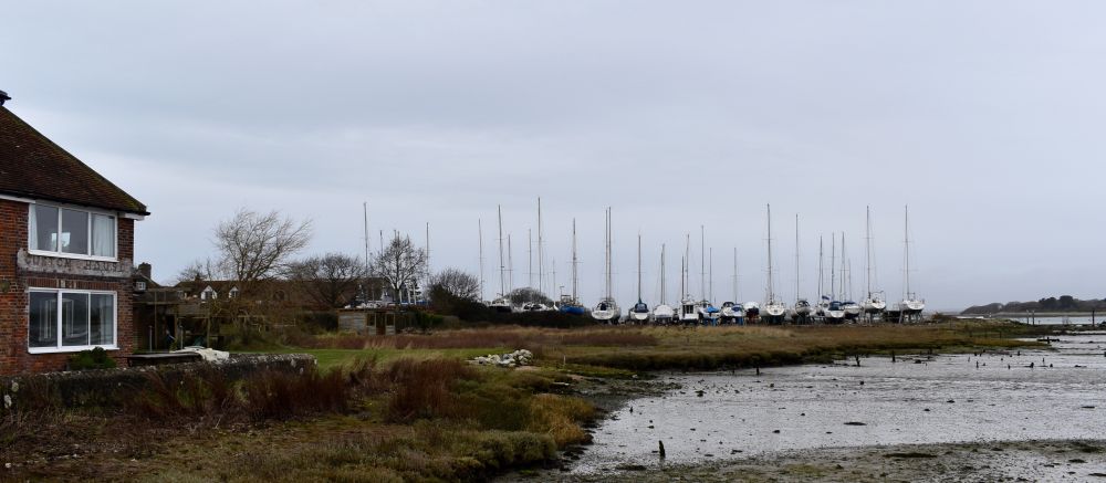 The site of Chitty and Vernon's former 1740s shipyard at Itchenor on Chichester Harbour. Nothing of the yard is now visible, but it lay between the house on the left and the laid-up yachts in the distance. The yard had at least two launching slips.