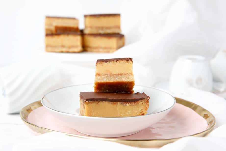 Caramel slice squares sitting on a pink plat on a white background.