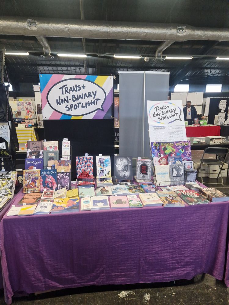 A table at a convention with comics labelled Trans and non binary spotlight 