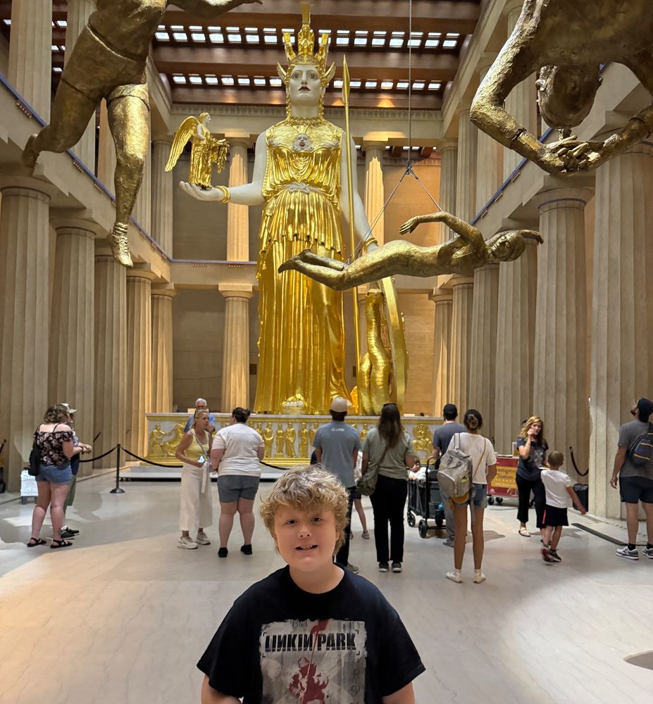 Giant golden statue replica of Athena at the Parthenon in Nashville Tennessee with a smiling boy in a Lincoln Park shirt that just had his dream come true. 