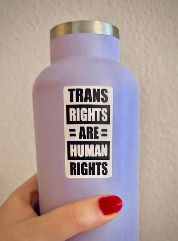 Purple water bottle with a sticker on it that says TRANS RIGHTS ARE HUMAN RIGHTS